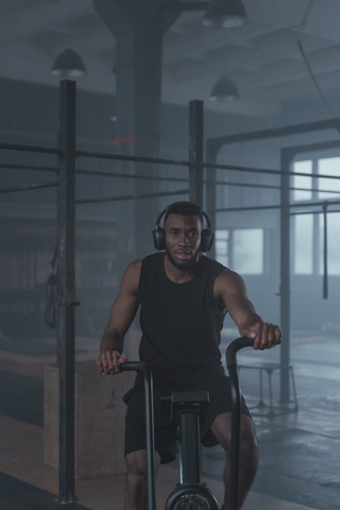 Man working out on a stationary bike in a gym, focused and determined.